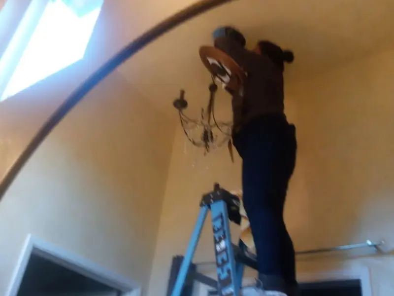 Electrician installing a chandelier in a Crystal City residence